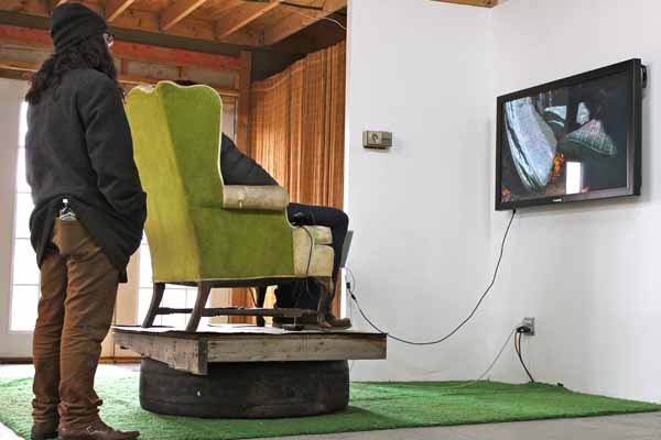 Gallery visitors watching "GARBAGE TOTEM #1 CLEARING A PATH TO THE FUTURE" - a collaborative video by Design 99 (2011).