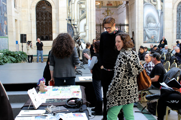 Reader Mike Lala (center) stands by the audio station where you can listen to the poets reading their own work.