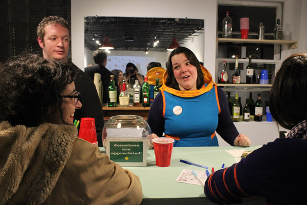 The artist in her signature tour-guide vest and self-designed hood, holding court behind the lifelike bar installation at Hatch.