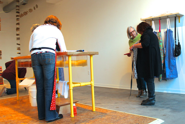 Attendees of the preview, jumping in on the action around the paper-making station.